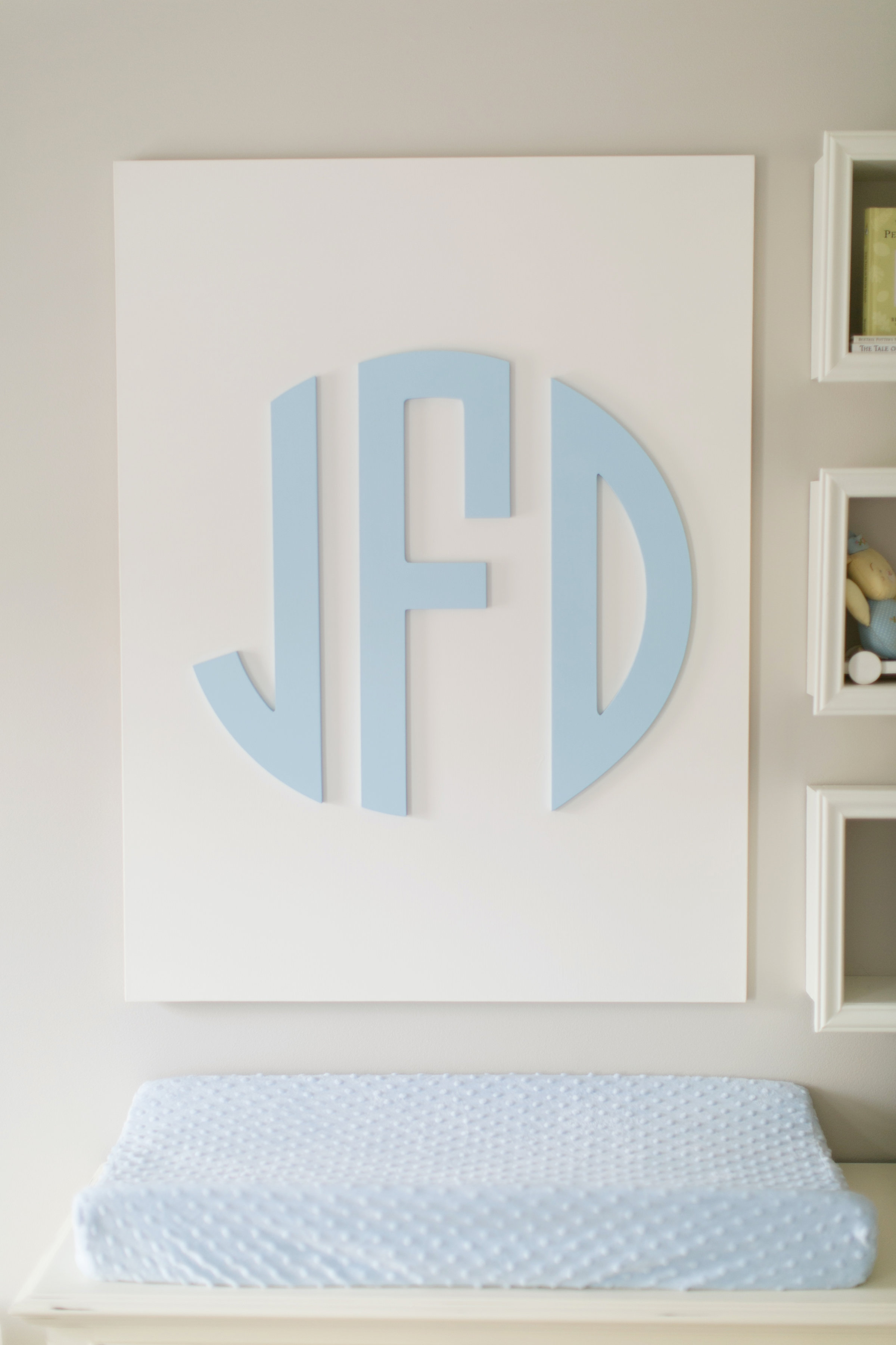 custom wood monogram wall decor hanging above a changing pad in a nursery room 