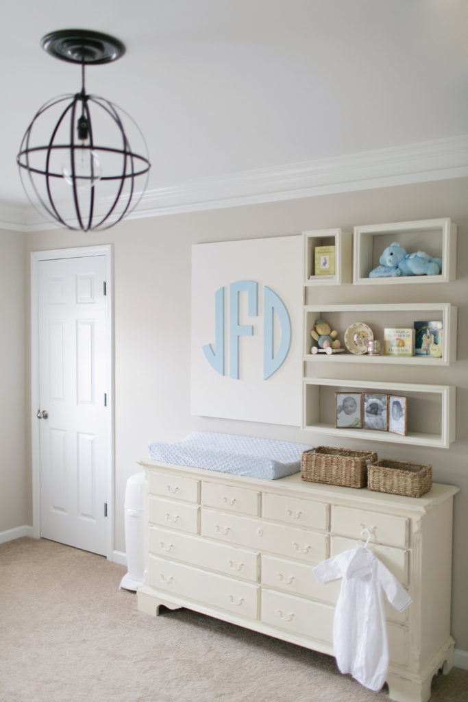 custom wood monogram wall decor hanging on the wall over a blue changing pad in a nursery