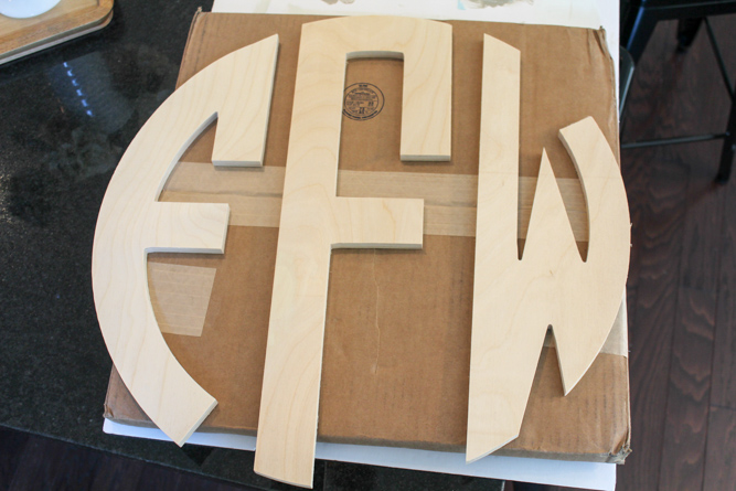 a custom wood monogram sitting on top of a cardboard box ready to be painted