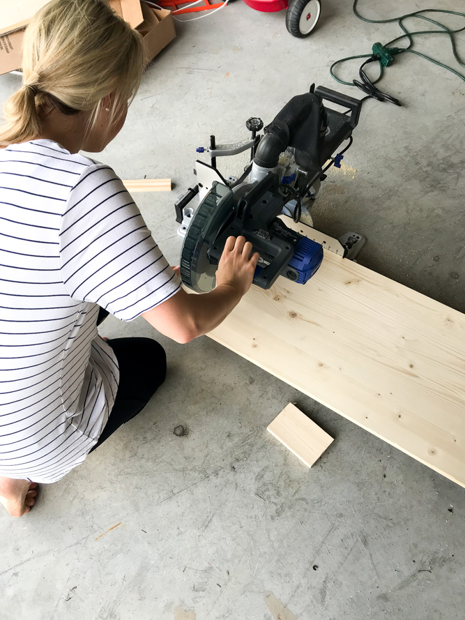 using a miter saw to cut a piece of wood to make a shelf