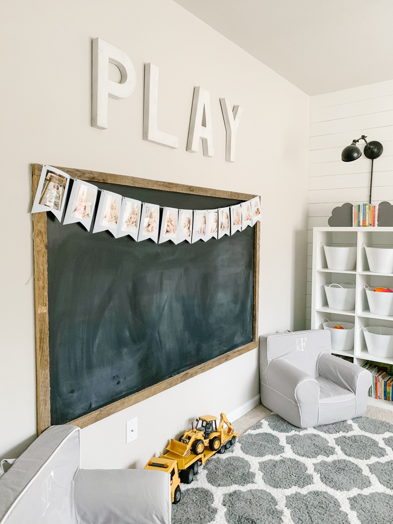 an oversized chalk board hangs on the wall in a children's playroom 