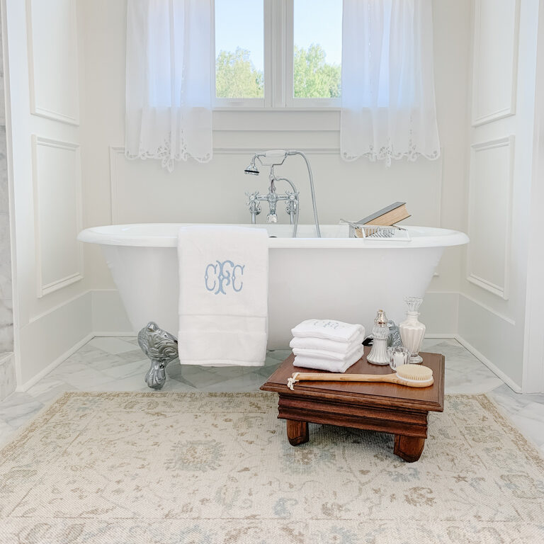 a bathroom with a white clawfoot tub and a vintage oriental style rug