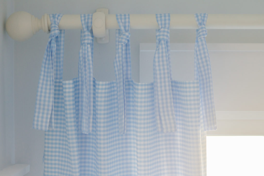 blue and white gingham tie-top curtains hanging on a curtain rod 