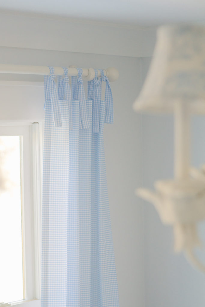 blue and white gingham tie-top curtains in the background of a nursery room