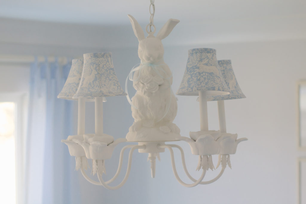 Light blue and white bunny fabric covered chandelier lampshades on a bunny chandelier in a nursery 