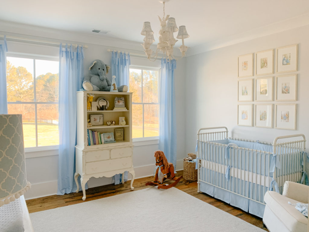 two sets of blue and white gingham tie-top curtains hanging on curtain rods in a decorated blue and white nursery 