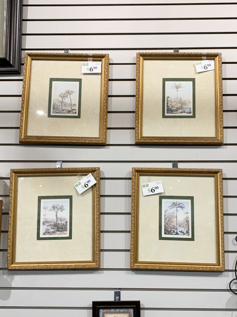 set of four gold picture frames hanging in the thrift store