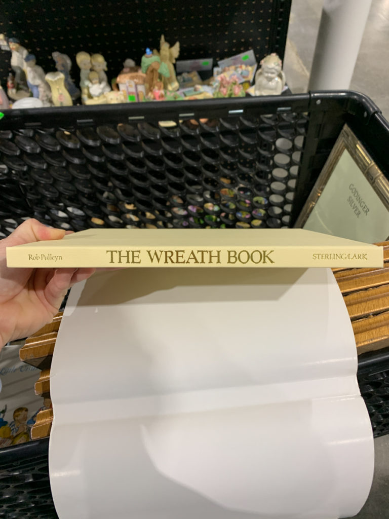 a hardcover book titled "The Wreath Book" for sale in a thrift store 