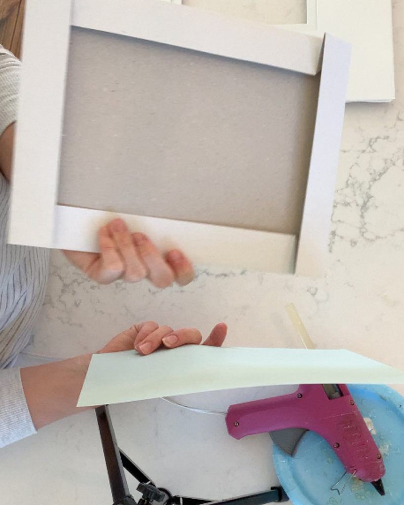glueing a piece of scrapbook paper onto a cardboard box for DIY framed intaglios