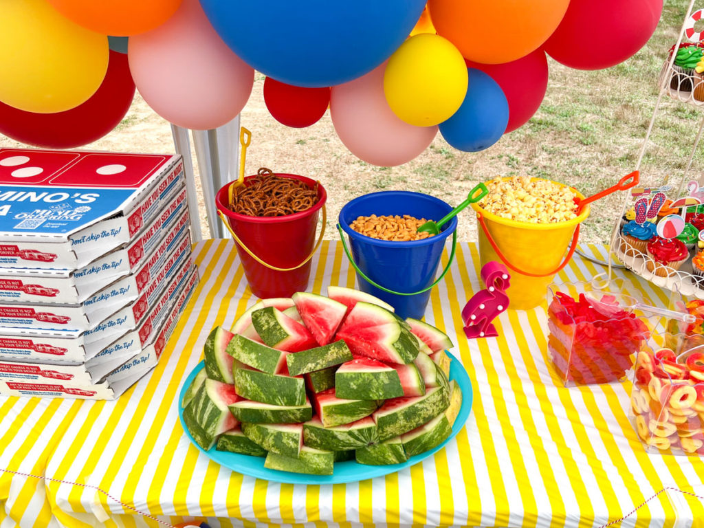 sliced watermelon on a teal platter on top of a yellow and white stripe tablecloth 