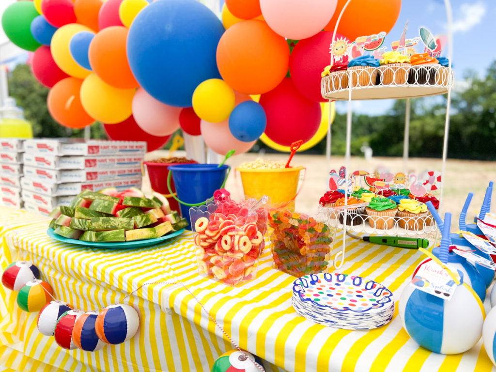 colorful cupcakes with summer themed cupcake toppers displayed in a cupcake stand at a summer waterslide birthday party 