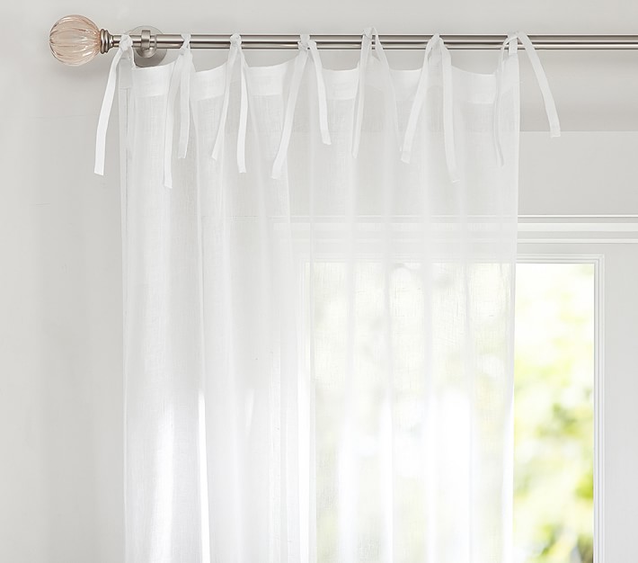 white Pottery Barn tie-top curtain panels hanging on a curtain rod 