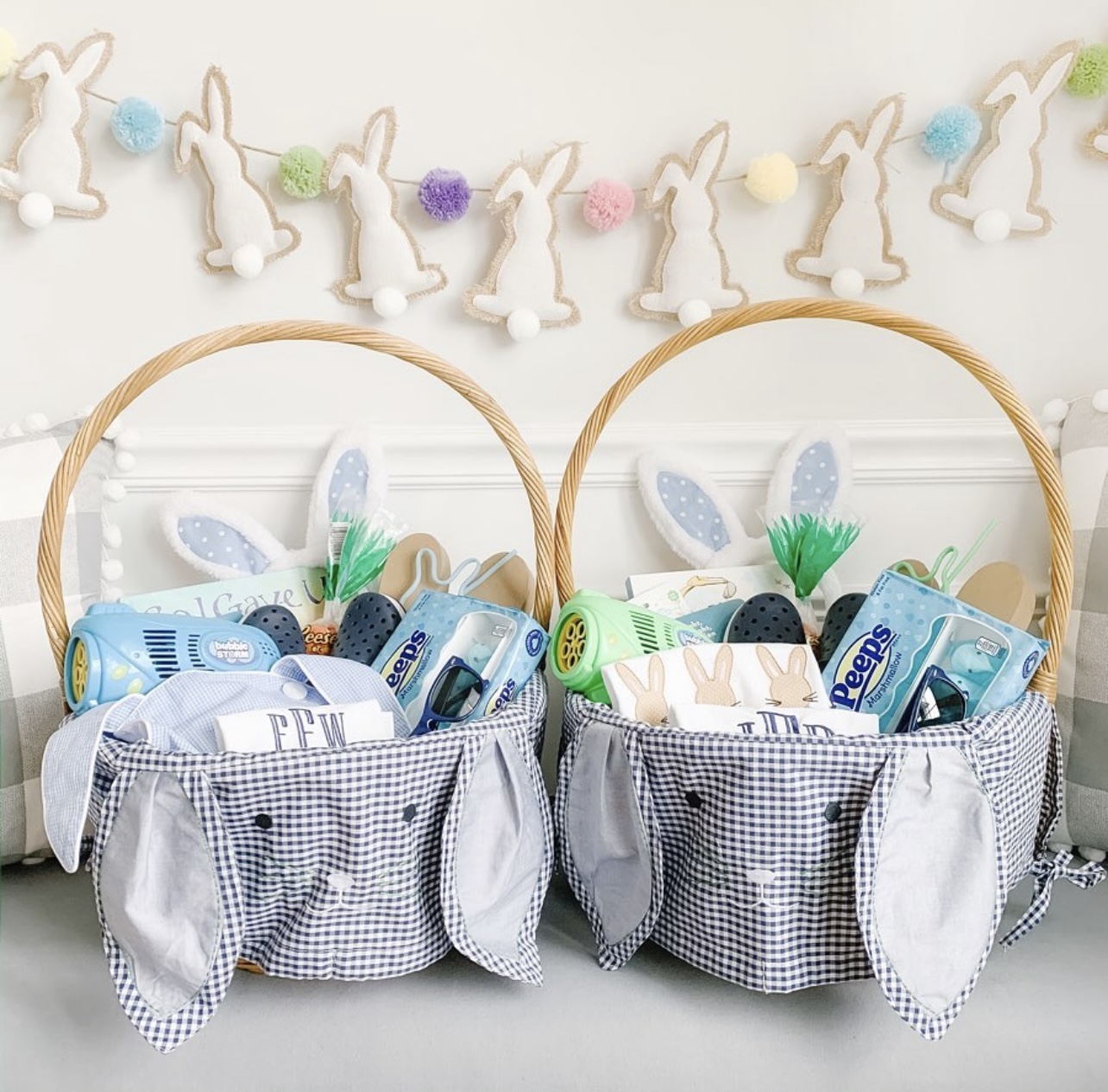 two easter baskets with blue gingham bunny liners filled with fillers sitting in front of a bunny banner