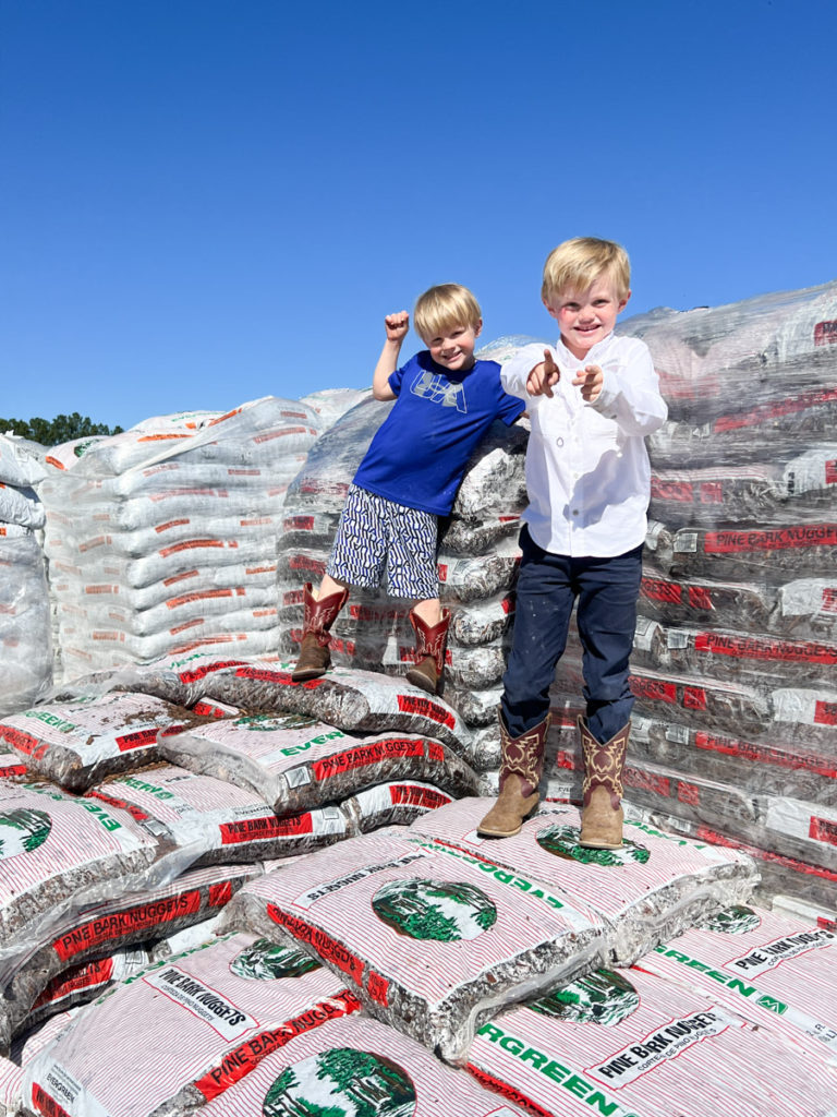two boys standing on a pile of mulch bags to build an easy diy playground border