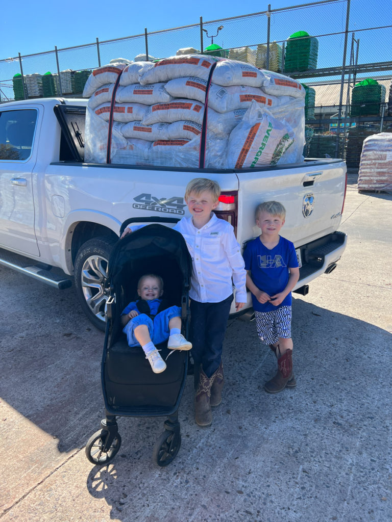 boys standing in front of a truck loaded with bags of pine bark to build an easy diy playground border
