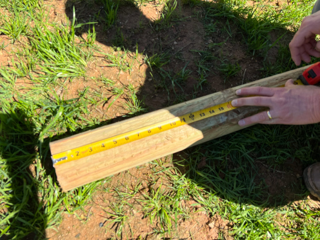 a measuring tape pulled across a landscape timber to build an easy diy playground border