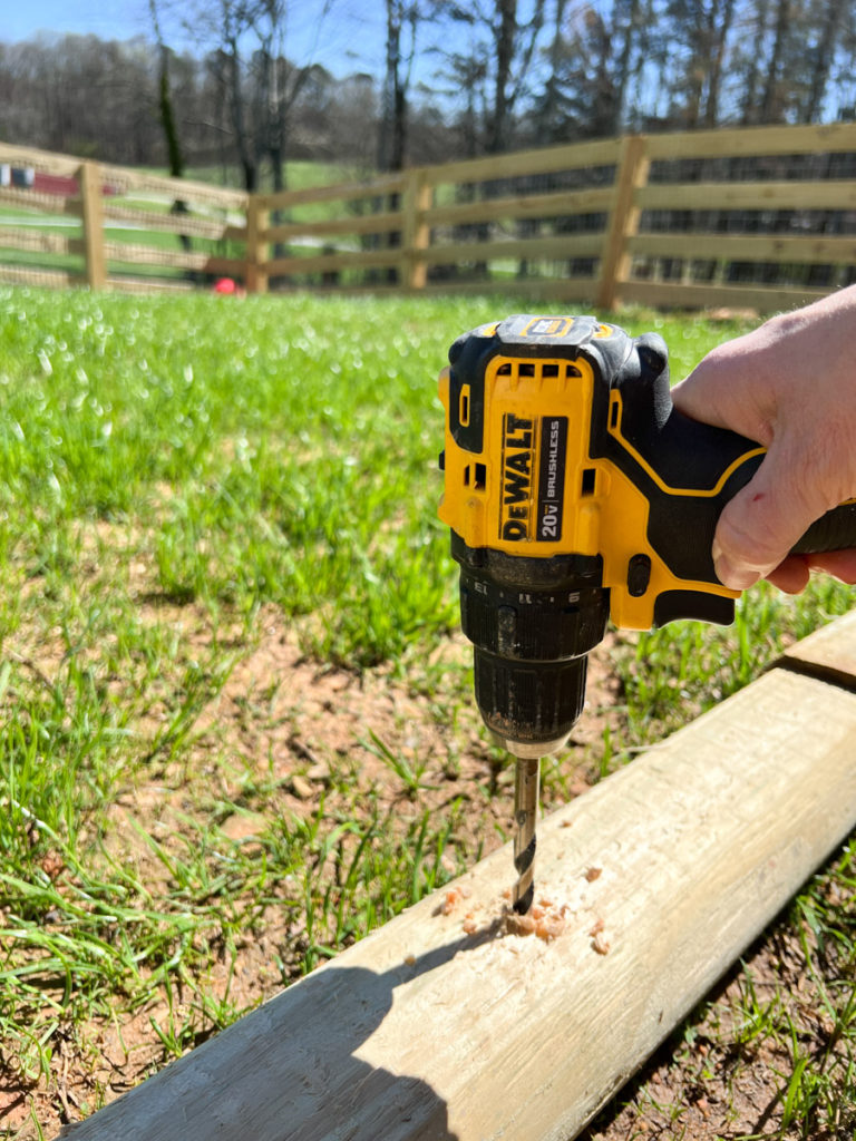 a dewalt drill drilling a hole into a landscape timber