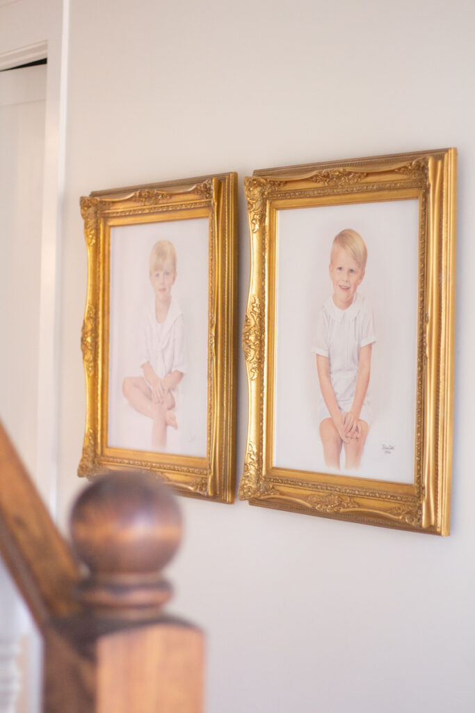 two framed light oil portraits in a foyer 