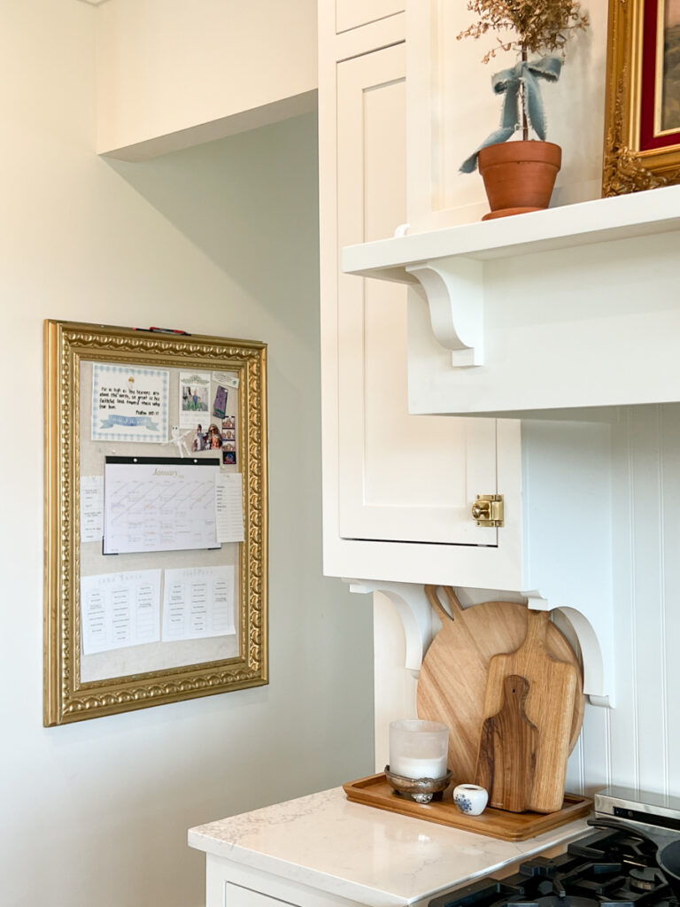 a family command center with a gold frame hangs on the wall in a kitchen 