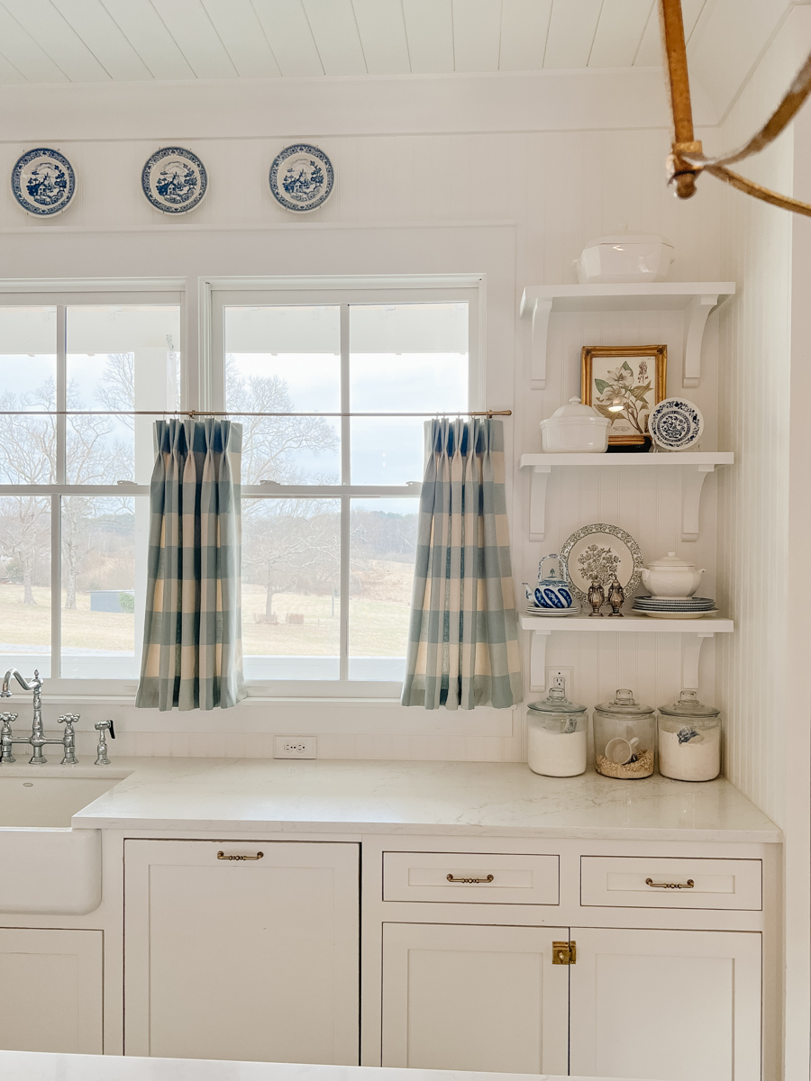 a white farmhouse kitchen with open shelving and a beadboard backsplash
