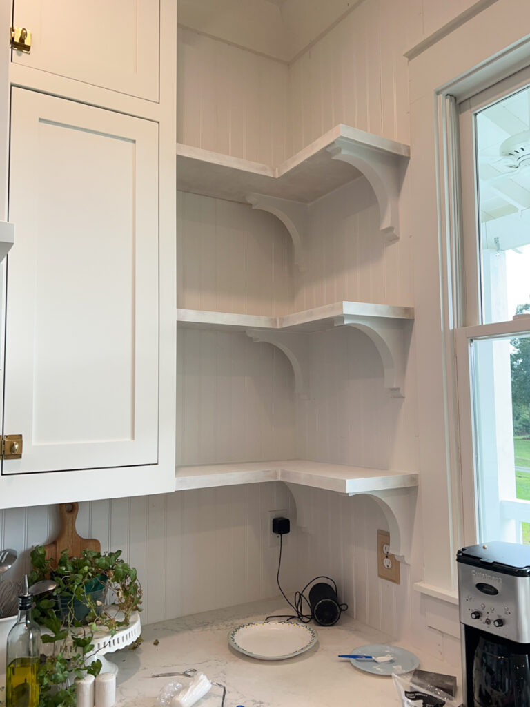 corner open shelves in a kitchen painted white 