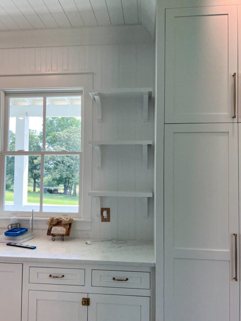 open shelves with corbels in a kitchen painted white 