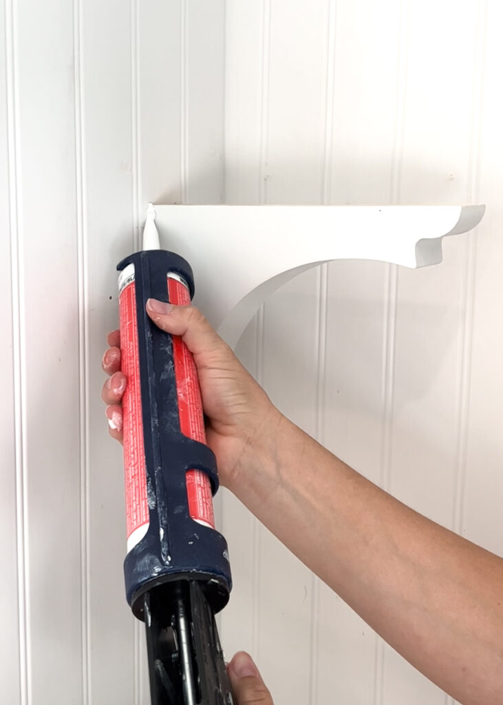 caulking a wood corbel that is hanging on the wall in a kitchen