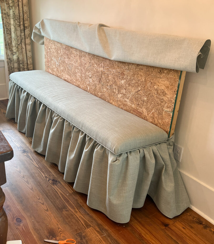 the construction process of a DIY banquette bench with an upholstered seat cushion and ruffled skirting