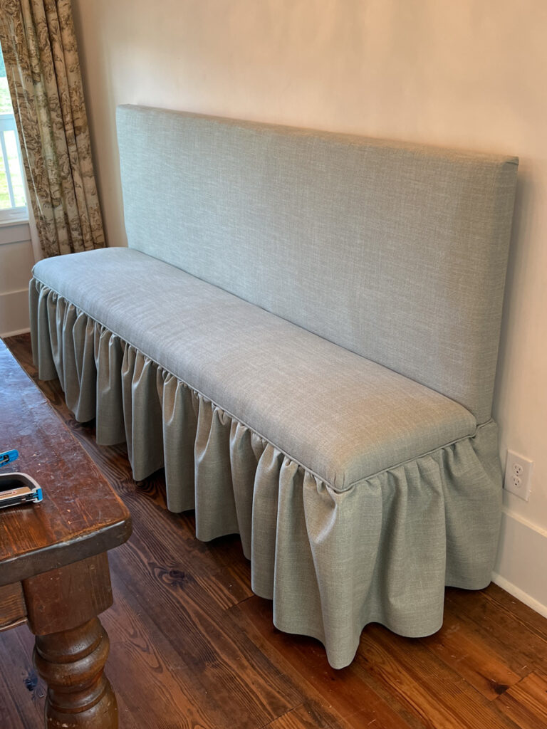 a custom upholstered DIY banquette bench with ruffled skirting 