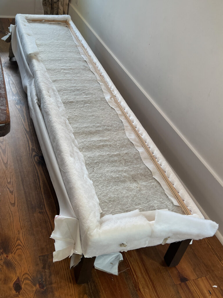 an upholstered bench taken apart down to the batting 