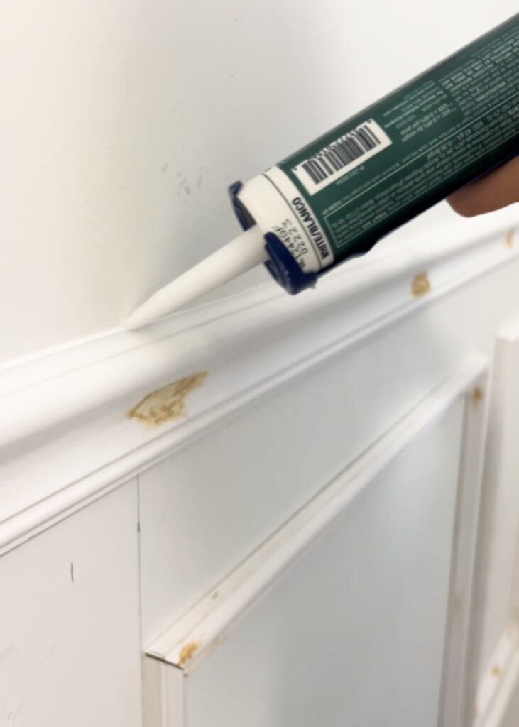 caulk being applied to picture frame molding trim 