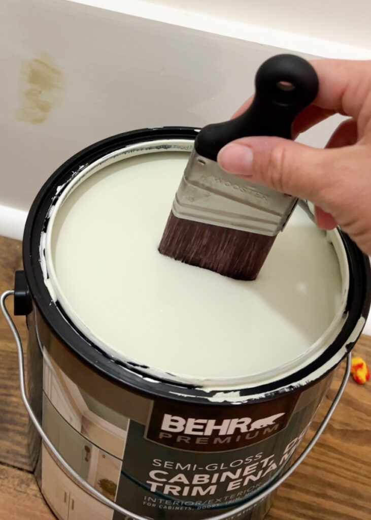 paint brush being dipped in a can of Behr paint