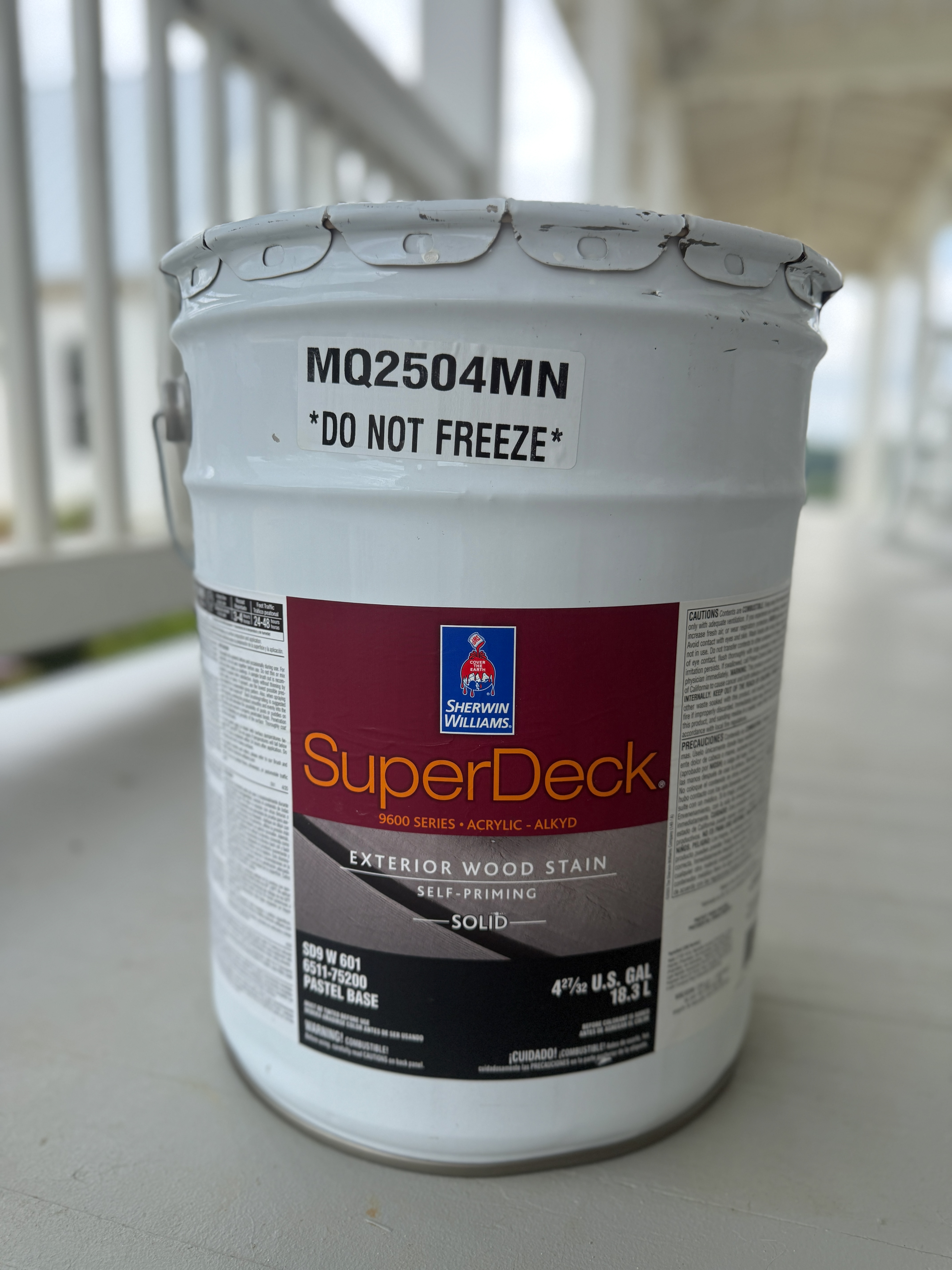 a five gallon bucket of Sherwin Williams SuperDeck 9600 Exterior Wood Stain sitting on a porch floor