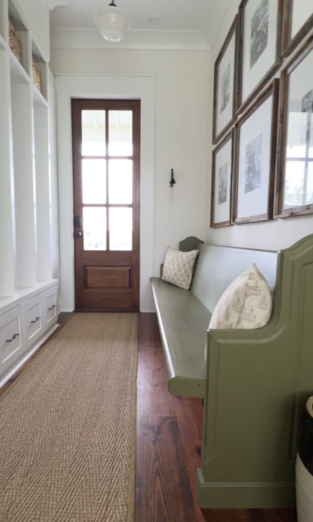 a mudroom with built in lockers and a green bench with a long sisal runner rug